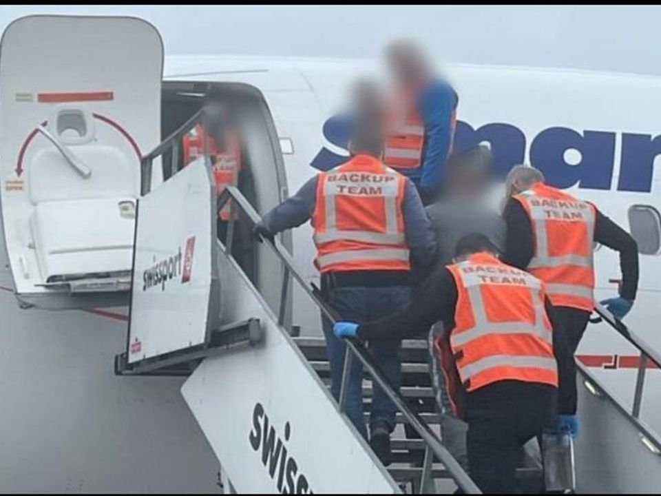 One of the deportees is escorted onto the aircraft